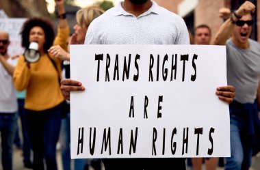 Unrecognizable black man protesting with crowd of people for transgender rights on public demonstrations. 