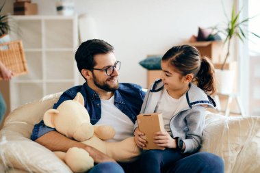 Happy father and daughter talking while moving into a new home. 