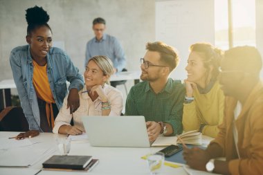 University students communicating while studying in team and using laptop in the classroom. 