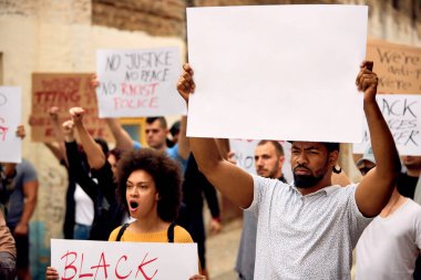 Young black man empty banner while marching with group of protesters against on anti-racism protest. Copy space. 