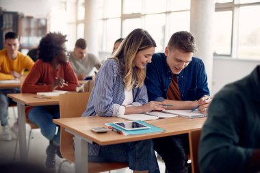 Happy students cooperating while studying lecture during class at university classroom. 