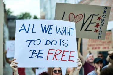 Close-up of a person holding banner with All we want to do is be free inscription while taking a part in a protest for human rights. 