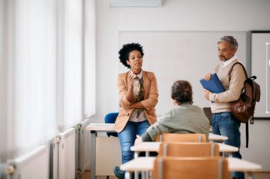 Black female teacher having consultations with adult students after a class at lecture hall. 