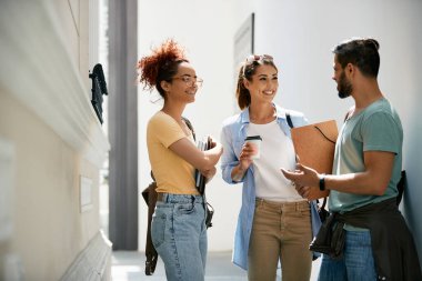 Group of happy college friends communicating on a break in hallway.