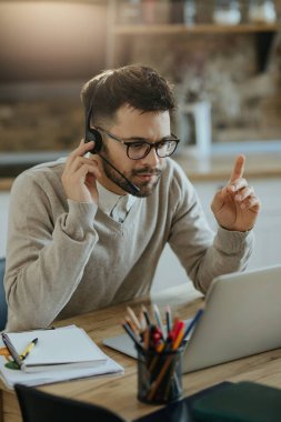 Young entrepreneur having conference call over a computer while working at home. 