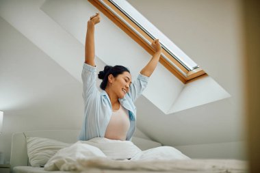 Mutlu Asyalı kadın sabah yatağında uyanırken geriniyor..