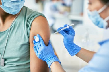 Close-up of black man getting vaccinated against coronavirus at vaccination center.