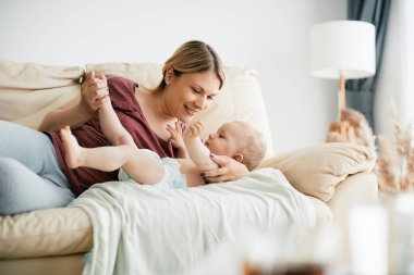 Smiling mother spending time with her baby son at home. 