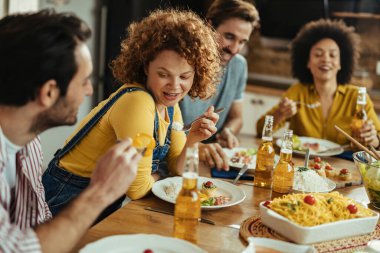 Group of friends having lunch together at dining table Focus is on redhead woman. 