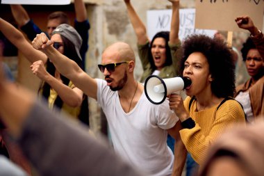 Young black woman shouting through megaphone on anti-racism solidarity protest. 