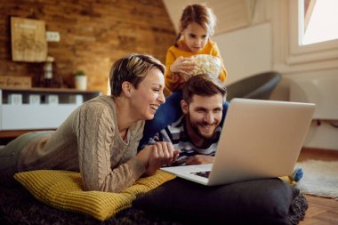 Happy family surfing the net on a computer while relaxing at home. Focus is on woman.