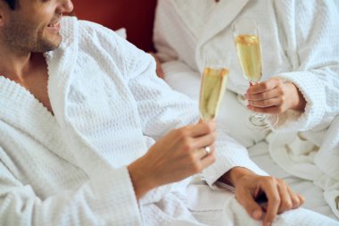 Close-up of married couple in bathrobes toasting with Champagne. 