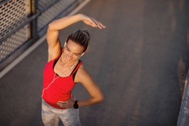 High angle view of happy athletic woman doing relaxation exercises and before sports training outdoors. 