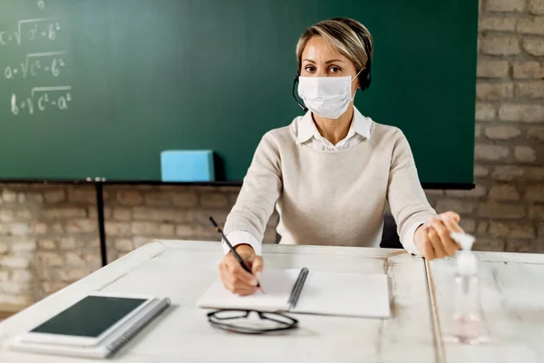 Female teacher giving online lecture to her students from the classroom during coronavirus pandemic.