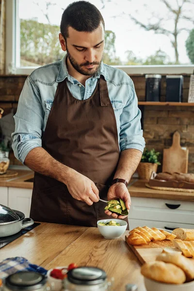 Young Man Peeling Avocado While Preparing Food Kitchen — 스톡 사진