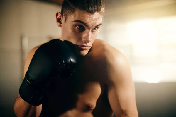 Young male fighter with black boxing gloves working out in boxing club.