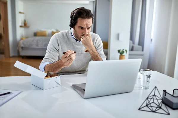 Distraught Male Entrepreneur Having Meal While Working Laptop Home — Stockfoto