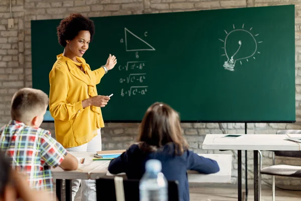 Happy African American Teacher Talking School Children While Explaining Them — Stok Foto