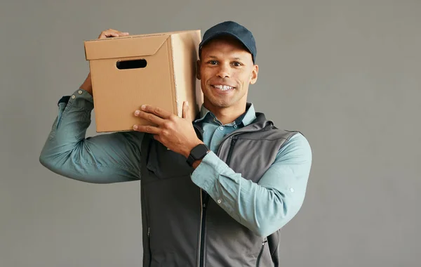 Happy courier carrying a package on his shoulder while making delivery and looking at camera. Copy space.