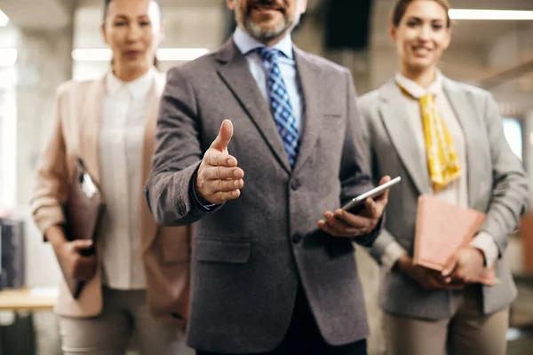 Close-up of company manager and his business team welcoming someone in the the office.