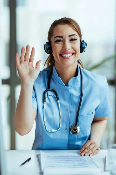 Happy healthcare worker waving while working at medical call center.