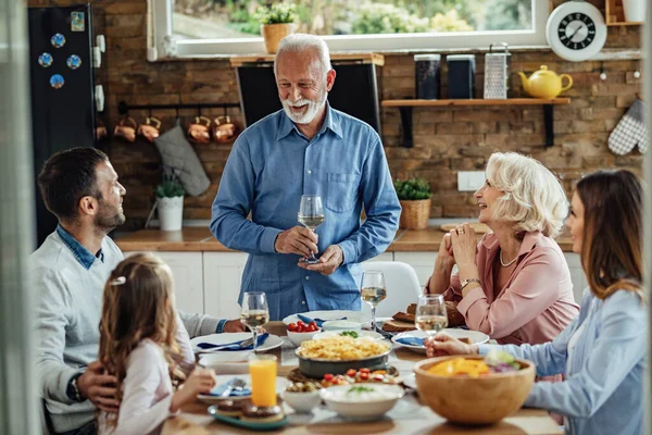 Happy Senior Man Holding Toast While Having Lunch His Family — Foto Stock
