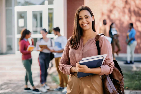 Happy university student going on a class at the university and looking at camera.