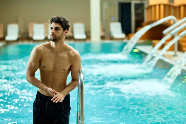 Young muscular build man getting out of the pool while spending a day at the spa.