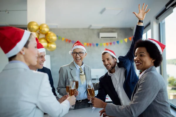 Happy mature businesswoman and her colleagues toasting with Champagne while celebrating on Christmas party in the office.