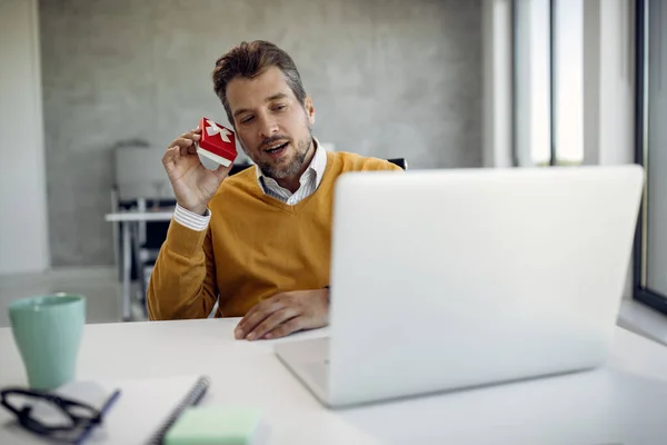Curios Businessman Shaking Gift Box While Having Video Call Laptop — Φωτογραφία Αρχείου