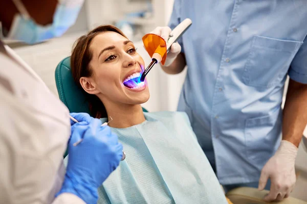 Young woman getting dental filling drying procedure with curing UV light at dental clinic.