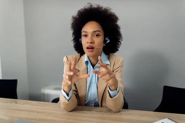 Black businesswoman making conference call in the office and looking at camera.