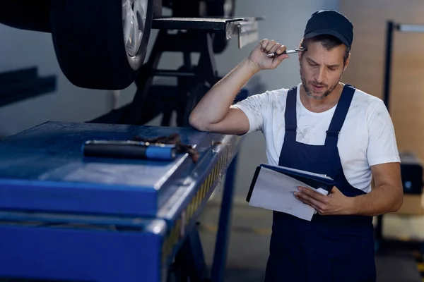 Pensive Mechanic Reading Paperwork While Examining Car Auto Repair Shop — Photo