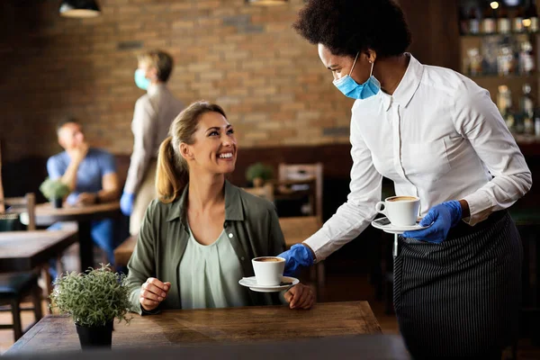 Happy Black Waitress Serving Coffee Female Guest While Wearing Protective — Foto Stock