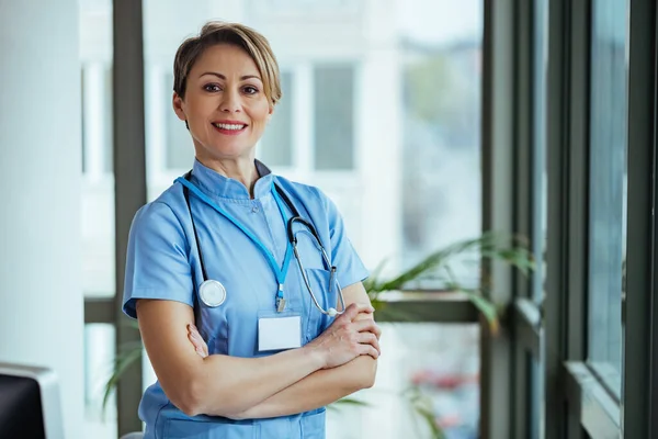 Portrait of happy confident nurse standing with arms crossed at the hospital.