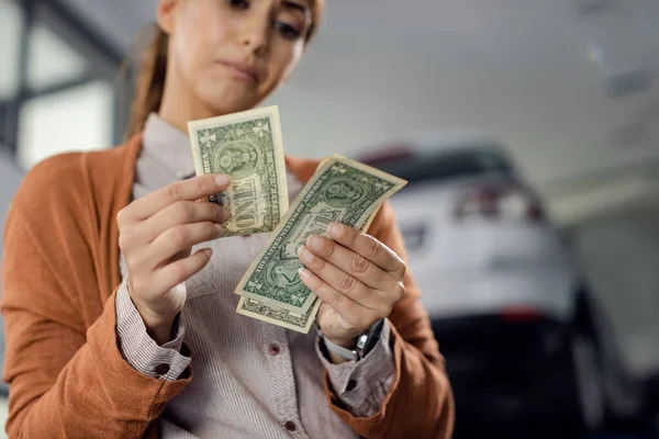 Close-up of female customer counting money while waiting for her car to be repaired at workshop.