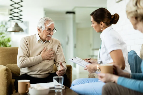 Mature Man Communicating Female Doctor Complaining Chest Pain Home Visit — Fotografia de Stock