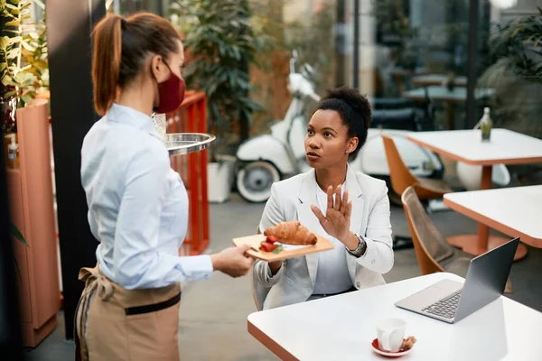 Displeased Black Businesswoman Rejecting Food Served Waitress Who Wearing Face — Foto Stock