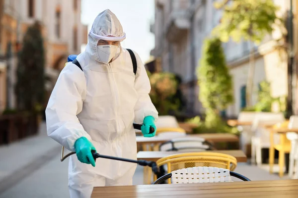 Sanitation Worker Protective Suit Doing Disinfection Outdoor Cafe Due Coronavirus — Stock fotografie