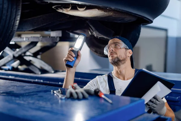 Mid Adult Repairman Using Flashlight While Examining Undercarriage Car Auto — Fotografia de Stock