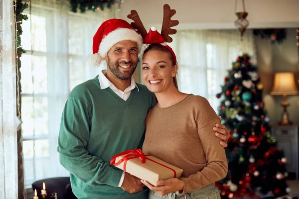 Happy Couple Holding Christmas Present Home Looking Camera — ストック写真