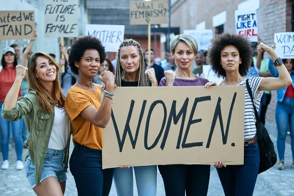 Multi-ethnic group of females flexing their biceps while participating in a protests for women\'s rights.