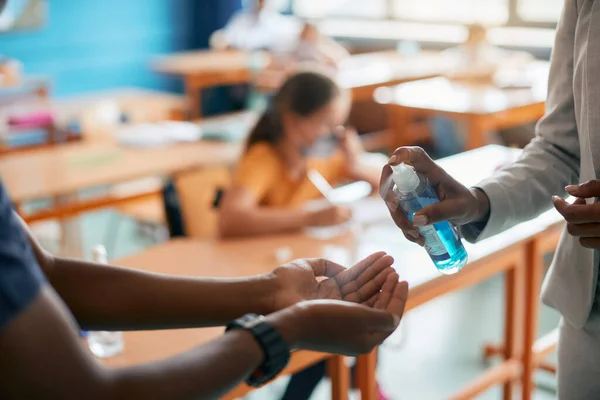 Close Elementary School Teacher School Boy Using Hand Sanitizer Classroom — Stok Foto