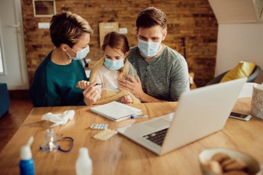 Parents with ill daughter wearing protective face masks at home due to virus pandemic. 