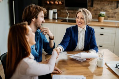 Mutlu sigorta acentası genç çiftle evlerinde tokalaşırken.. 