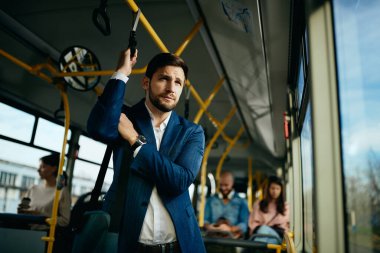 Businessman looking through the window and thinking while traveling to work by bus.