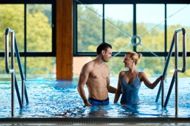 Smiling couple getting out of thermal pool and talking while enjoying a day at the spa. 