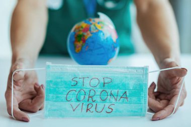 Close-up of healthcare worker holding N95 face mask with stop coronavirus inscription. 