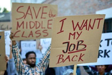 Close-up of crowd of people protesting against unemployment on public demonstrations. Focus is on banner with 'I want my job back' inscription. 