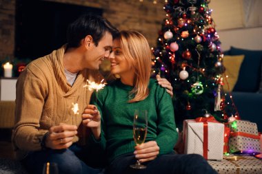 Sevecen çift burunlarına dokunurken maytap kullanıyor ve Noel arifesinde evde şampanya içiyor.. 